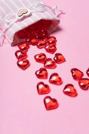 selective focus. Valentine's day card. glass red hearts scattered from a beautiful cloth bag. the view from the top. pink backgroundの写真素材