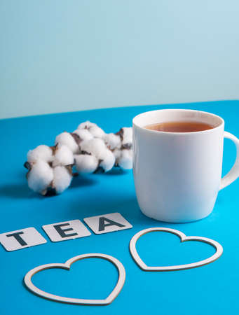 selective focus: Ceylon black tea in a white mug on a blue plain paper background. copyspace. cardboard letters laid out in the word Tea in Englishの写真素材