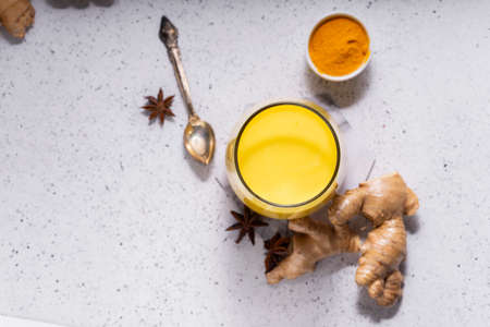 selective focus. Healthy ayurvedic drink golden almond milk or pumpkin turmeric latte with curcuma powder on white background. copy space.Trendy Asian natural detox beverage with spices for vegansの写真素材