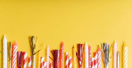 yellow birthday flatlay. colored paper tubes with wax candles. holiday concept, greeting card. copyspaceの写真素材
