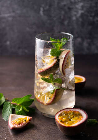 refreshing drink with passion fruit. cocktail with tropical fruit on a dark background. with green mint leaves. vertical positionの写真素材