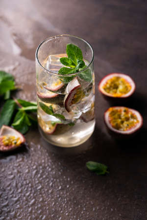 refreshing drink with passion fruit. cocktail with tropical fruit on a dark background. with green mint leaves. vertical positionの写真素材