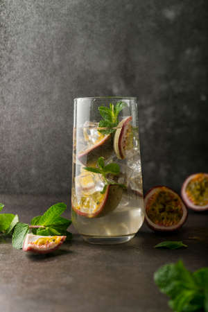 refreshing drink with passion fruit. cocktail with tropical fruit on a dark background. with green mint leaves. vertical positionの写真素材
