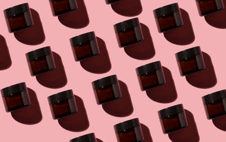 color pattern on a pink background. glass jars for natural cosmetics with hard shadows. for...