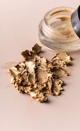 broken eye shadow scattered across the smooth pink surface. Texture background, advertising the...