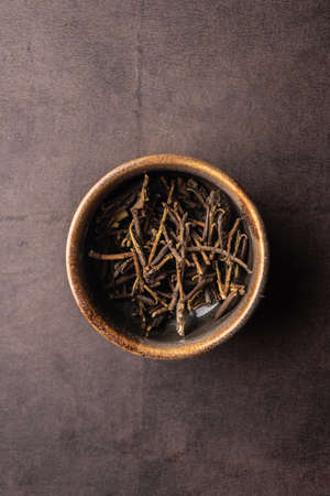selective focus, natural green leaf tea. brewing in a clay bowl. vertical angle, macro. on a dark background. for menus and cafesの写真素材