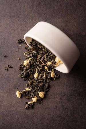selective focus, natural black leaf tea with jasmine flowers. brewing in a clay bowl. vertical angle, macro. on a dark background. for menus and cafesの写真素材