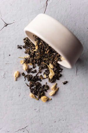 selective focus, natural black leaf tea with jasmine flowers. brewing in a clay bowl. vertical angle, macro. on a light background. for menus and cafesの写真素材