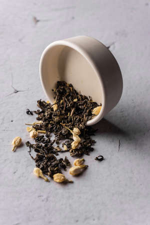 selective focus, natural black leaf tea with jasmine flowers. brewing in a clay bowl. vertical angle, macro. on a light background. for menus and cafesの写真素材