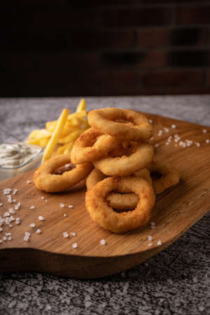 selective focus. fried onion rings in breadcrumbs fried in oil. with natural sauce. restaurant serving. on a dark background. for menus and adsの写真素材