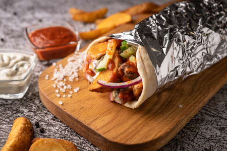 doner kebab, a shawarma in a pit of fresh vegetables and meat. with large spices. restaurant serving. on a dark background. for menus and adsの写真素材