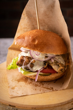 juicy meat burger with fresh vegetables and spices. soft fragrant bun and natural sauces. side view. on a dark background, for menus and adsの写真素材