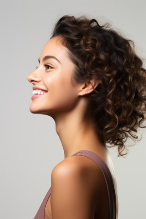 side view of smiling young woman with curly hair, isolated on greyの素材
