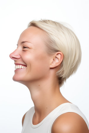 Portrait of a beautiful young woman with short blond hair smiling on white backgroundの素材