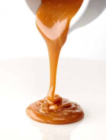 pouring sweet caramel sauce on a white backgroundの写真素材