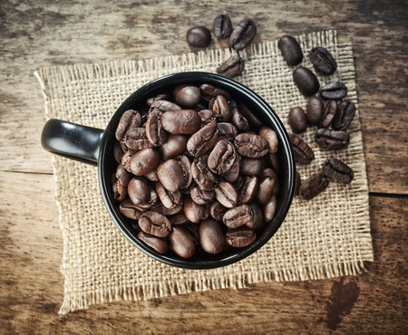 cup of coffee beans on old wooden tableの写真素材