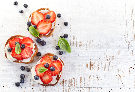 toasted bread with cream cheese and strawberries on white wooden tableの写真素材