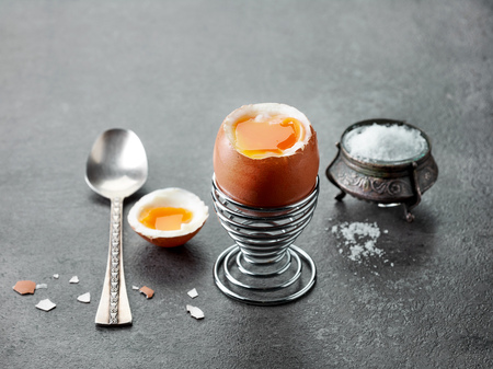 freshly boiled breakfast egg on dark grey kitchen tableの写真素材