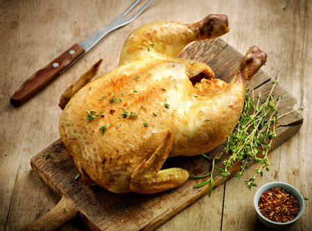 whole roasted chicken on wooden cutting boardの写真素材