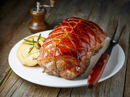 roasted pork on white plate on rustic wooden kitchen tableの写真素材