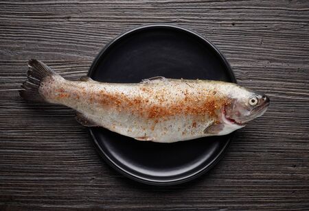 fresh raw spicy trout fish on wooden kitchen table, top viewの写真素材