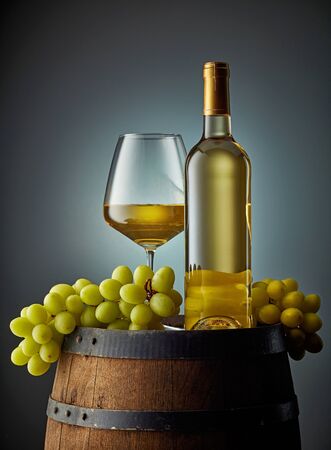 glass and bottle of wine on old wooden barrelの写真素材