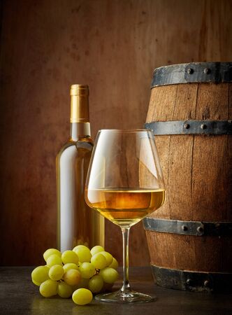 glass and bottle of white wine on wooden backgroundの写真素材