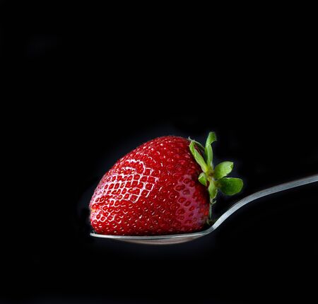 fresh ripe strawberry in silver spoon on black backgroundの写真素材