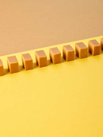 line of caramel candies on colorful paper backgroundの写真素材