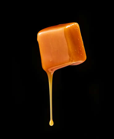 Caramel sauce flowing on flying caramel candyの写真素材