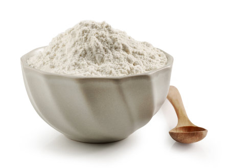 bowl of flour and wooden spoon isolated on white backgroundの写真素材