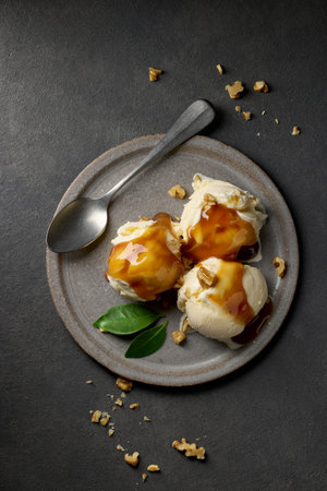 plate of vanilla ice cream with caramel sauce and walnut on dark grey background, top viewの写真素材