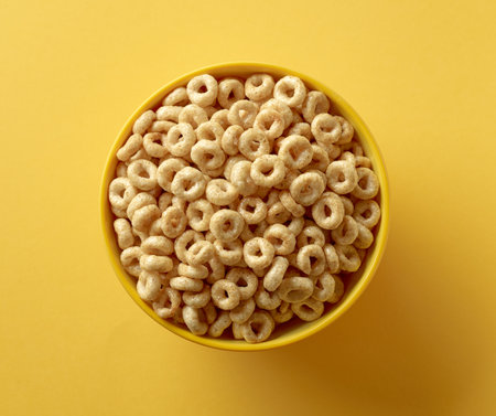 bowl of breakfast cereal honey rings isolated on yellow background, top viewの写真素材