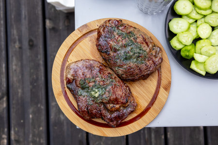 freshly grilled juicy beef steaks on wooden cutting board, top view