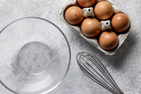 bowl and eggs on light grey painted kitchen table background, top viewの写真素材
