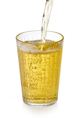 yellow apple juice pouring into glass isolated on white backgroundの写真素材
