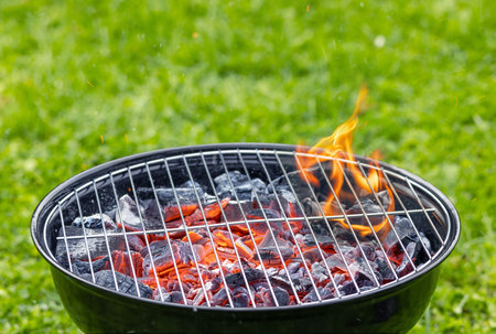 burning charcoal grill on green grass backgroundの写真素材