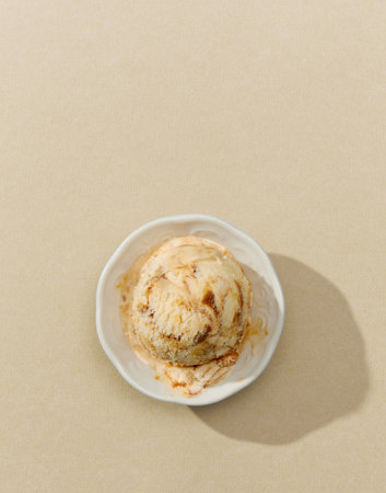 bowl of caramel ice cream isolated on beige background, top view