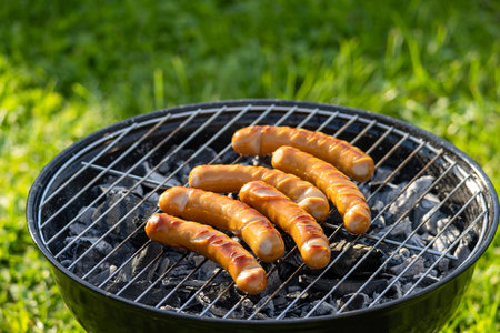 freshly grilled sausages on charcoal grill in the gardenの写真素材