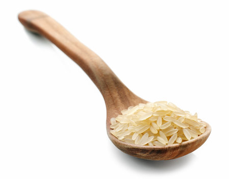 raw rice in wooden spoon isolated on white backgroundの写真素材