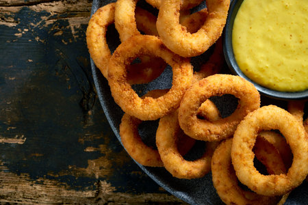 plate of fried onion rings and sauce on old wooden table, top viewの写真素材
