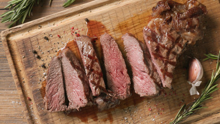 freshly grilled sliced steak on wooden cutting board, top viewの写真素材