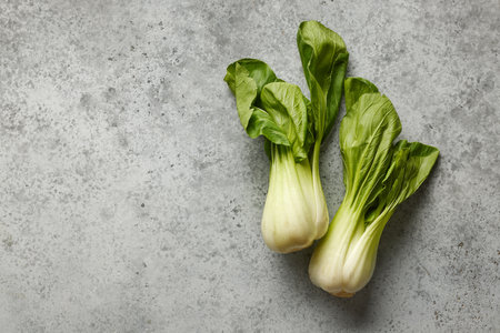 fresh raw green pak choi lettuce or chinese cabbage on grey table background, top view. Paksoiの写真素材