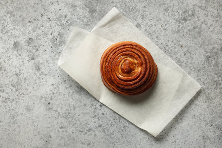 freshly baked sweet cinnamon roll on gray table, top view