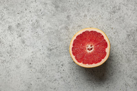half of fresh red juicy grapefruit on grey kitchen table, top viewの写真素材