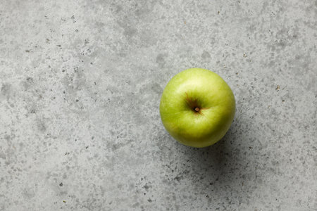 fresh green apple on grey kitchen table background, top view