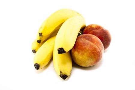 Fresh bananas and peaches on white backgroundの写真素材