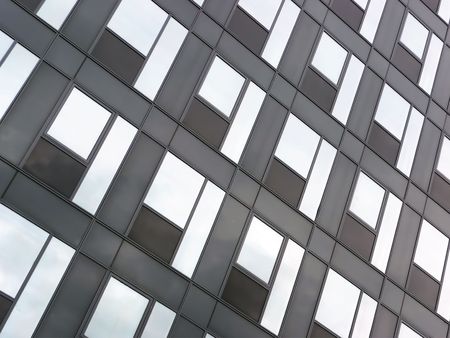 Modern black glass facade reflecting blue sky with clouds