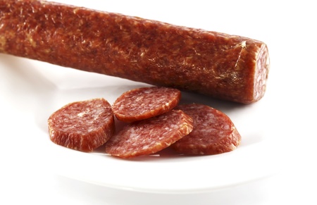 Smoked sausage cut by slices on a white dishの写真素材
