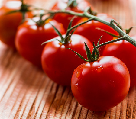Small cherry tomatoes on the wooden background. Closeup, selective focus.の写真素材